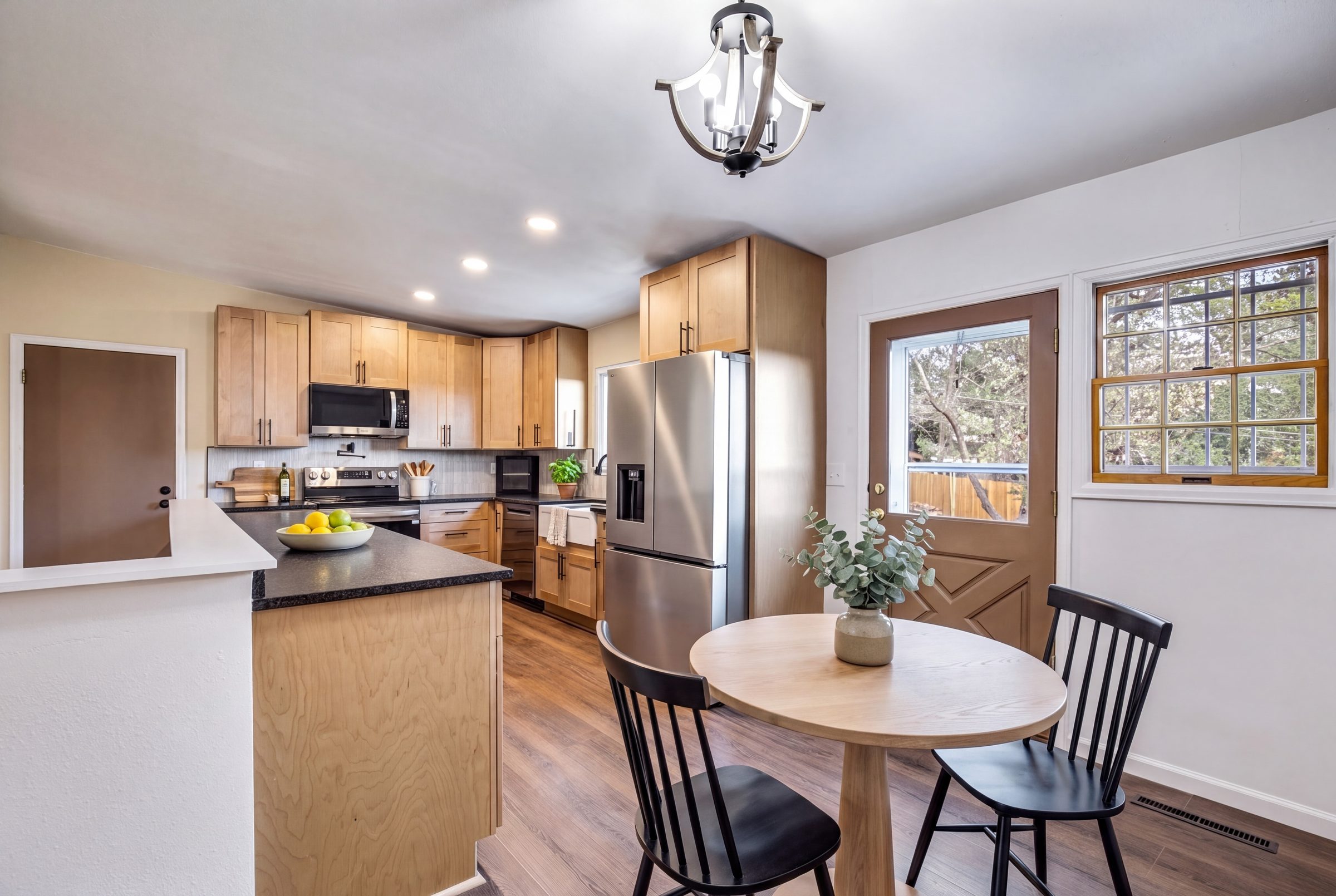 Remodeled kitchen with leather granite and stainless appliances, staged with a round dining table